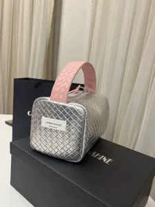 Detail einer silber-rosa geflochtenen Kosmetiktasche mit Tragegriff und Reißverschluss.