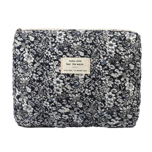 Macro view of a quilted navy floral cotton cosmetic bag showing texture and label