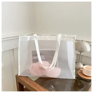 Bolso tote grande de malla blanca transparente con una gorra rosa en su interior
