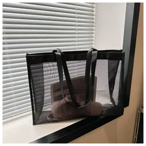 Vista detallada de un bolso tote de malla negra transparente con textura y capacidad.