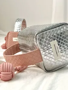 Nahaufnahme der Webstruktur und des Design-Labels auf der silber-rosa Kosmetiktasche