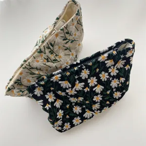 Embroidered daisy pouches in black and cream showing detailed floral patterns.