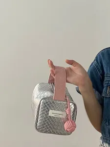 Detailaufnahme einer gewebten Make-up-Tasche in Silber und Rosa, handgehalten