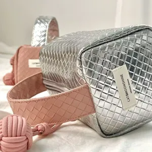 Detailansicht der silber-rosa geflochtenen Kosmetiktasche mit dekorativem Knotengriff