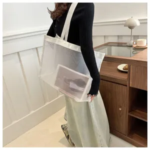 Bolso tote grande de malla blanca minimalista para verano, lucido por una modelo.