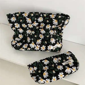 Close-up detail of black fabric pouches with white daisy embroidery and Sozakka label tags