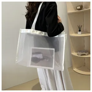 Vista detallada de un bolso tote de malla blanca grande y minimalista llevado al hombro