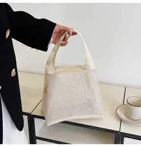 Detail view of white nylon mesh cosmetic bag showing sturdy handles and breathable texture.