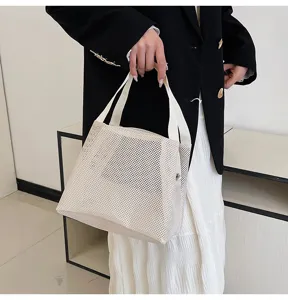 Minimalist beige nylon mesh cosmetic bag held by a person for beach or travel