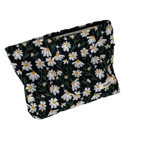 Elegant black makeup pouch featuring white daisy embroidery and secure zipper closure