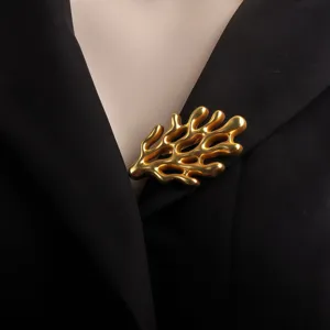 Macro detail of a matte gold coral-shaped brooch pinned on a stylish black blazer lapel