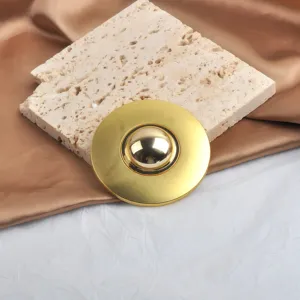 Macro detail view of a polished gold mirror-finish round metal brooch for suit decoration
