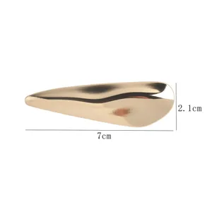 Détail macro d'une broche en métal doré ondulé avec dimensions de 7 cm par 2,1 cm