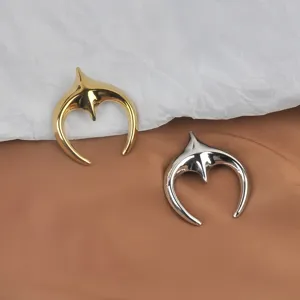 Detailed view of polished stainless steel crescent moon brooches in gold and silver finish