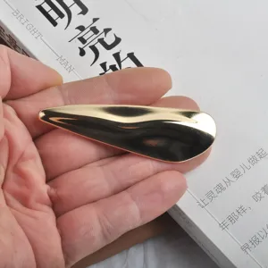 Détail d'une broche moderne ondulée dorée de forme irrégulière avec une finition brillante