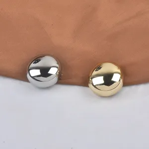 Detailed close-up of gold and silver smooth round metallic brooches on brown fabric