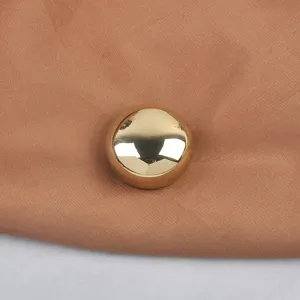 Detailed macro view showing the polished mirror finish of a round gold metallic brooch