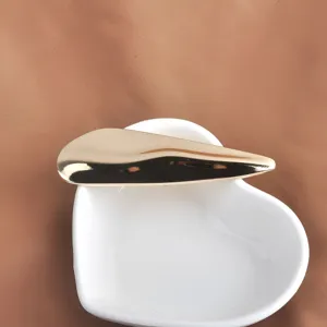 Vue détaillée d'une broche dorée minimaliste en forme de vague sur un plat cœur
