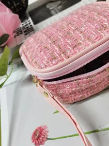 Gros plan d'une élégante pochette en tweed rose avec des fils dorés brillants.