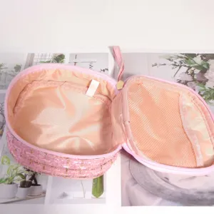 Vue détaillée du mini sac cosmétique en tweed rose avec poche filet et doublure satin.