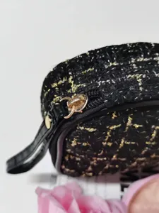 Gros plan de la trousse cosmétique en tweed noir et or avec fermeture éclair