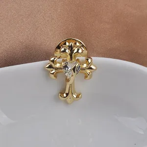 Detailed close-up of a gold-plated cross brooch featuring a heart-shaped crystal stone