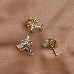Close-up of three gold cross and angel brooches with rhinestones on brown silk fabric