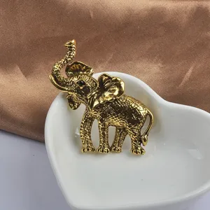 Gedetailleerde close-up van een gouden olifantspeld in een witte hartvormige schaal.