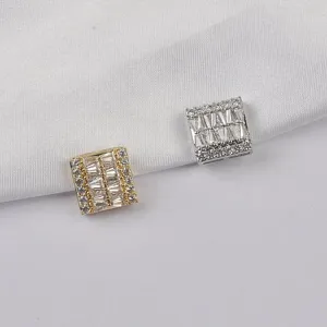 Detailed view of square magnetic brooches in gold and silver with sparkling baguette crystals