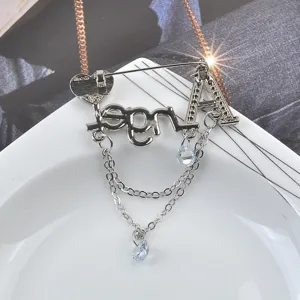 Detailansicht einer silbernen Angel-Brosche mit funkelnden Strasssteinen und Kettenquasten
