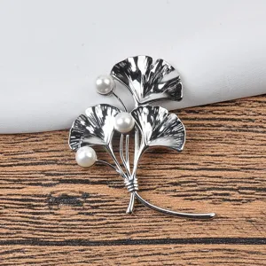 Detailansicht einer silbernen Ginkgoblatt-Brosche mit drei eleganten weißen Perlen