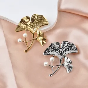 Detailansicht eleganter goldener und silberner Ginkgoblatt-Broschen mit Perlen