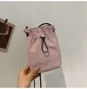 Vista detallada de un mini bolso bandolera minimalista de lona rosa con cordón