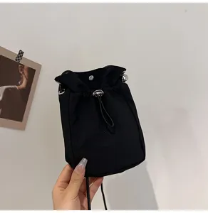 Detalle del mini bolso negro de lona para móvil con un práctico cierre de cordón y botón
