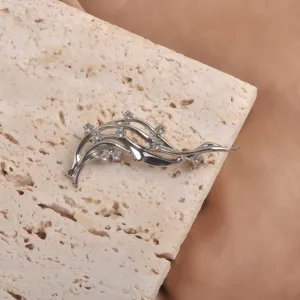 Vue détaillée d'une broche vague argentée artistique avec des strass brillants sur pierre