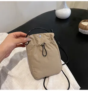 Vista detallada de un bolso para móvil de lona caqui con cordón y correa negra delgada