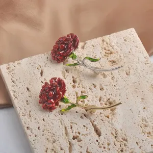 Close-up of red carnation brooches in gold and silver finishes on stone