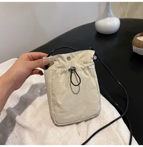 Mano sosteniendo un bolso para móvil de lona crema minimalista con cordón negro