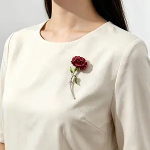 Detail of an elegant red carnation enamel brooch pin worn on a white blouse for women