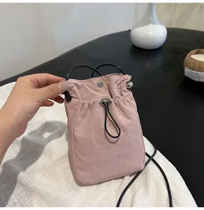 Vista detallada de bolsa para móvil de lona rosa con cierre de cordón y bandolera