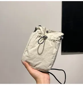 Primer plano de bolso para móvil minimalista en lona crema con cordón y cierre presión