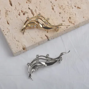 Gros plan de broches vagues dorées et argentées avec des accents de strass brillants