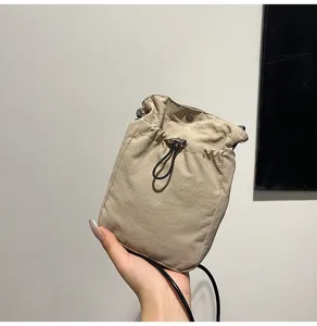 Primer plano de una bolsa de teléfono minimalista caqui con cordón sostenida en la mano