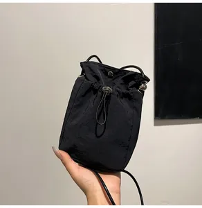 Vista de mano de este mini bolso bandolera negro minimalista con cordón ajustable