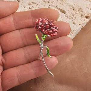 Detailed view of an enamel carnation brooch held by hand