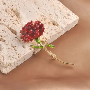 Close-up detail view of a red carnation brooch with enamel petals and a gold-tone stem