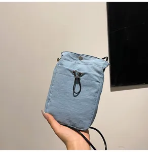 Primer plano de mini bolso de móvil azul claro con cordón ajustable en la mano