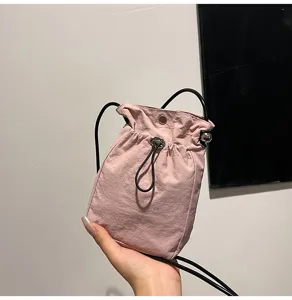 Primer plano de una mini bolsa rosa con cordón para móvil sostenida con la mano en detalle