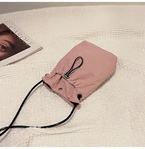 Detalle de bolso rosa minimalista con cordón sobre tela con textura