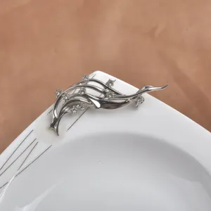 Élégante broche vague artistique argentée avec des strass étincelants sur une assiette blanche